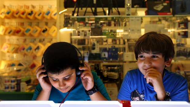 At the shops: Two boys listen to music in a store at Baghdad's Mansour Mall.
