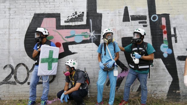 Volunteer first responders from the "Green Helmets" stand on the sidelines of an anti-government protest in Venezuela.