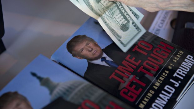 A guest pays for books near a book by Donald Trump at the summit in Ames, Iowa, on Saturday.
