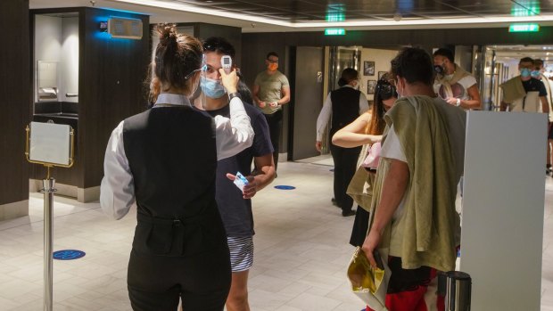 Passengers have their temperature checked as they enter a restaurant on board. 