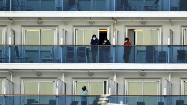 Passengers speak on balconies of the quarantined Diamond Princess cruise ship docked at a port in Yokohama.