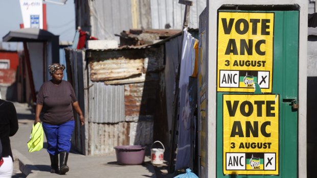 A woman walks near an African National Congress poster fixed on a toilet door in the township of Khayelitsha on the outskirts of Cape Town.