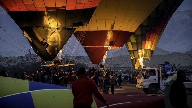 Hot-air balloons prepare to take-off as the sun rises.