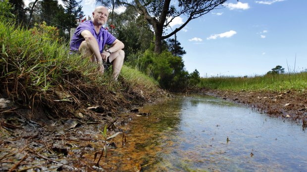 Salt Ash resident Rob Roseworne sits beside a contaminated drain which runs past the front of his property.