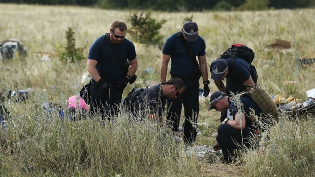 Australian Federal Police officers and their Dutch counterparts collect human remains from the MH17 crash site. 