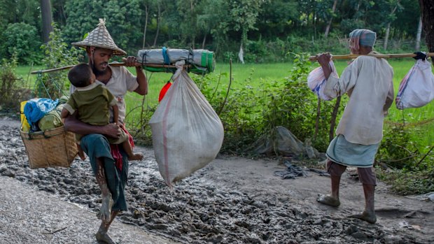 A Rohingya Muslim tries to balance his son as he carries his belongings near Balukhali refugee camp, Bangladesh.