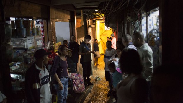 Residents wait for a gunfight to stop before walking to their homes during a police operation at Rocinha slum in Rio last month.