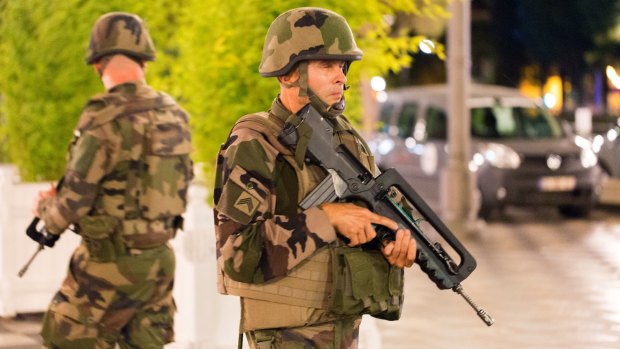 French soldiers stand guard by the sealed off area of an attack after a truck drove on to the sidewalk and ploughed through a crowd of revellers.