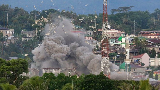 Debris flies in the air near a mosque minaret as Philippine Air Force fighter jets bomb suspected locations of militants in Marawi. 