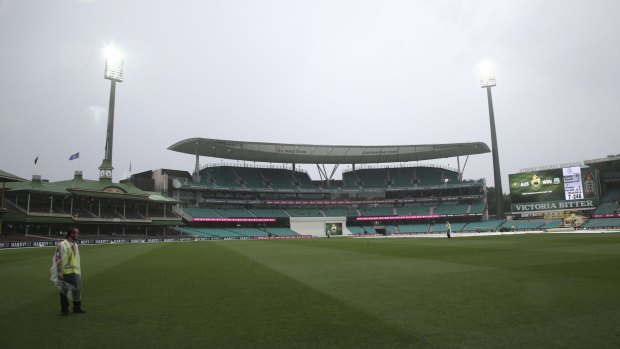 A security guard stands on the field at the Sydney Cricket Ground as play is abandoned due to inclement weather.