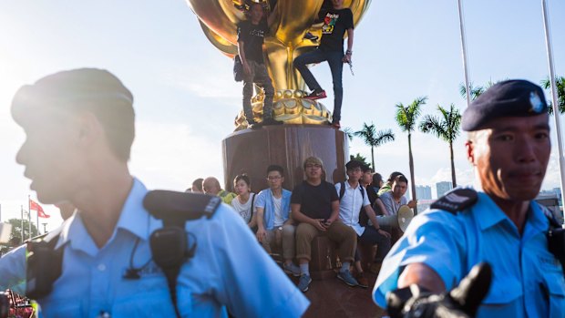 Hong Kong police officers stand guard as protesters gesture and shout slogans ahead of the visit by Chinese President Xi Jinping.