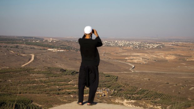 A Druze man watches fighting between forces loyal to Syrian President Bashar al-Assad and rebels in the Syrian village of Jubata al-Khashab from the Israeli-occupied Golan Heights on Sunday.