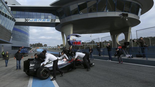 Jenson Button is pushed by members of his team during pre-season testing at the Jerez racetrack.