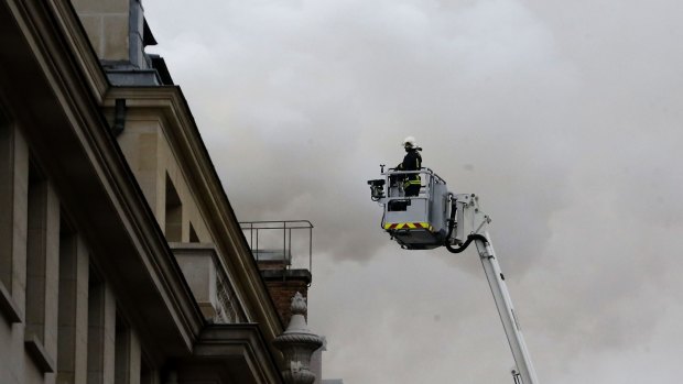 A French firefighter tackles the blaze on the top floor of the Ritz Paris hotel. 