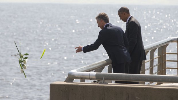 President Barack Obama watches as Argentinian President Mauricio Macri tosses roses into the river during their visit to Parque de la Memoria in Buenos Aires on Thursday.