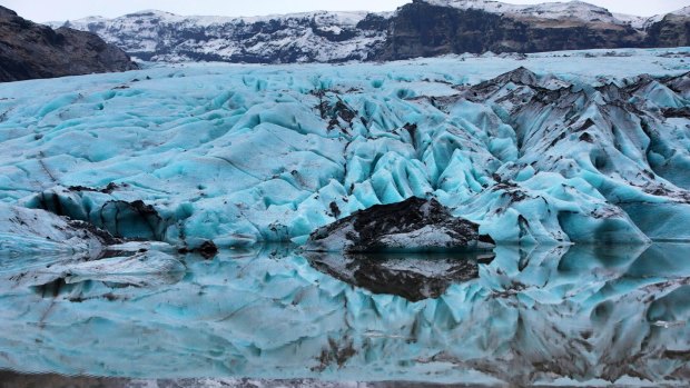 Solheimajokull Glacier's surface is white, but its layers grey and occasionally electric blue.