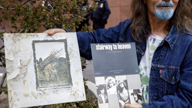 A Led Zeppelin fan holds up an album and sheet music for <i>Stairway to Heaven</i> outside of federal court in LA. 