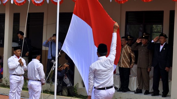 Ali Fauzi salutes the Indonesian flag. Dozens of former terrorist prisoners have been deradicalised in Indonesia.