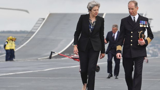 British Prime Minister, Theresa May, talks with Commodore Jerry Kyd, Captain of the 65,000-tonne British aircraft carrier HMS Queen Elizabeth, during her tour of the ship on Wednesday.