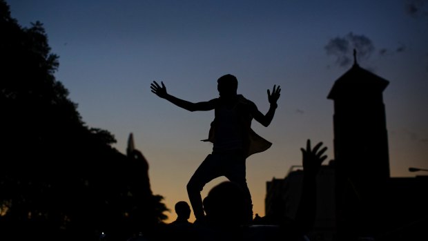 A Zimbabwean dances on the roof of a vehicle as he and others celebrate Mugabe's resignation in downtown Harare on Tuesday.