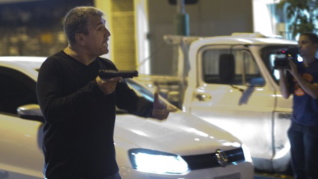 A man who identified himself as a police officer points his gun at anti-World Cup protesters blocking a road in Rio de Janeiro, in June 2014. 