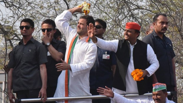 Uttar Pradesh state Chief Minister Akhilesh Yadav, red cap, and Congress party Vice President Rahul Gandhi, wearing tricolor shawl, throw flowers to the crowd.