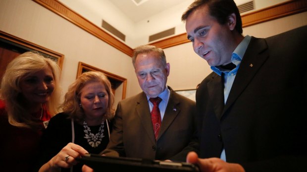Roy Moore, second from right, looks at election returns with staff during an election-night watch party on Tuesday.