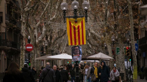 People walk past a poster of the No. 2 on the Republican Left's list, Marta Rovira, next to an independence flag, ahead of the Catalan regional election in Barcelona.