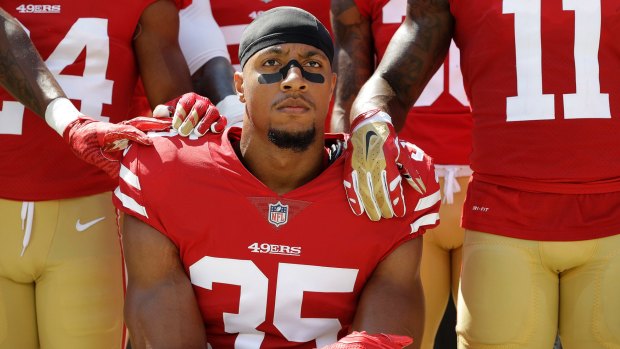 San Francisco 49ers' Eric Reid kneels in front of teammates during the playing of the national anthem.