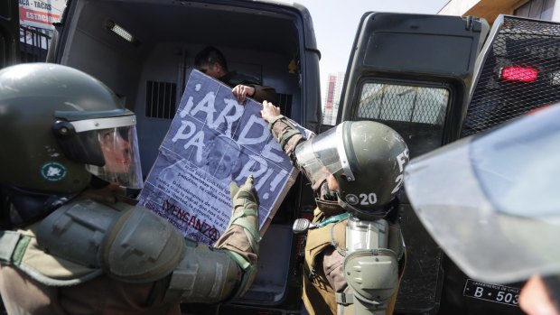 Chilean riot police take away a poster with an image of Pope Francis saying "Burn, Daddy" after several people were arrested during a protest in Santiago.