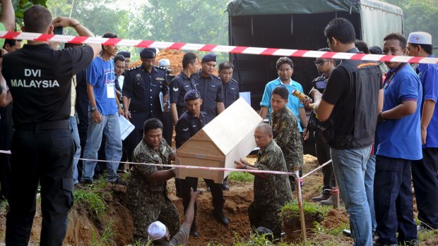 Malaysian police carry a coffin containing the remains of a Rohingya migrant in 2015. Mass graves were also discovered in southern Thailand.