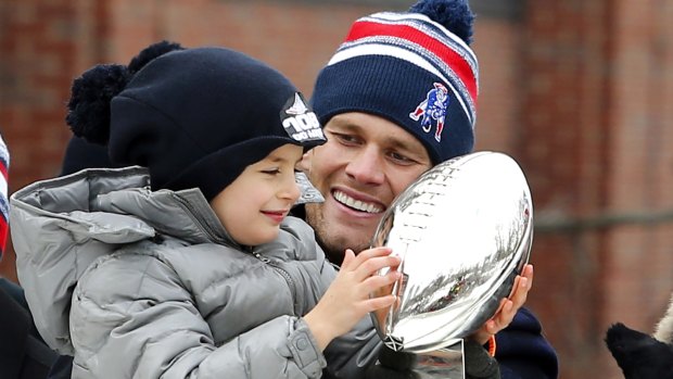 Patriots quarterback Tom Brady looks on as his son, Benjamin admires the Vince Lombardi Trophy.