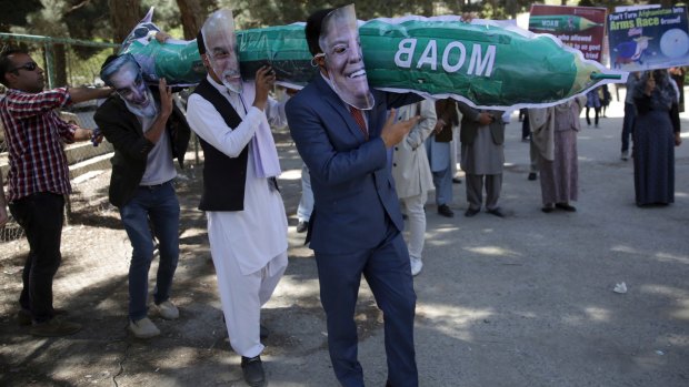 Afghans wearing masks of US President Donald Trump, Afghan President Ashraf Ghani and Afghan Chief Executive Abdullah Abdullah, carrying a handmade model of the "Mother of All Bombs" during a protest in Kabul on April 16.