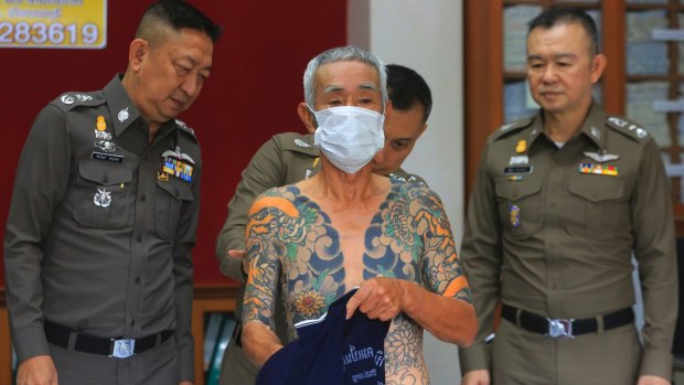 Japanese gang member Shigeharu Shirai displays his tattoos at a police station in Thailand.