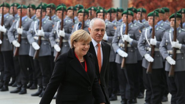 Germany's Chancellor Angela Merkel left, and Prime Minister Malcolm Turnbull review an honour guard during a welcoming ceremony prior to a meeting at the German Chancellery in Berlin.
