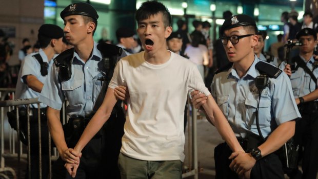 A pro-democracy activist is arrested by police in Golden Bauhinia Square ahead of the 20th anniversary celebrations.