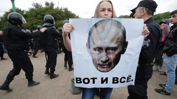 A woman holds a poster depicting Russian President Vladimir Putin with the slogan 'This is it' during an anti-corruption rally in St Petersburg on June 12.
