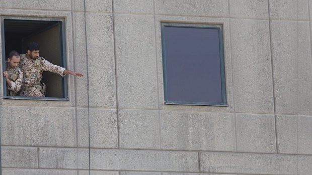 Men in military uniform stand at a window in the Iranian parliament building following the attack.