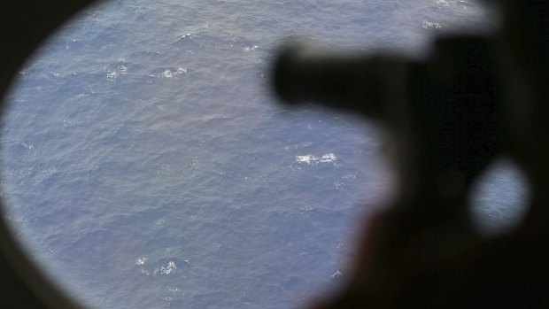 An observer on a Japan Coast Guard Gulfstream aircraft takes photos out of a window while searching for MH370.