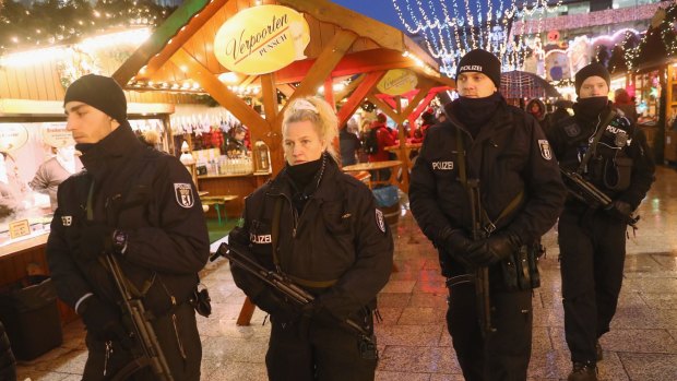 Heavily-armed police walk through the reopened Breitscheidplatz Christmas market.