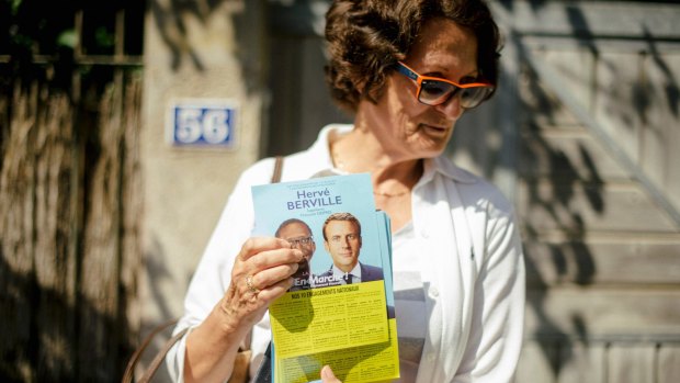 A supporter of Herve Berville, a candidate with the new La Republique en Marche party, holds a flyer at a market in St Jacut-de-la-Mer.