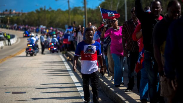 A demonstrator wearing a Haitian flag shirt walks past marchers during a protest against US President Donald Trump near Mar-a-Lago.