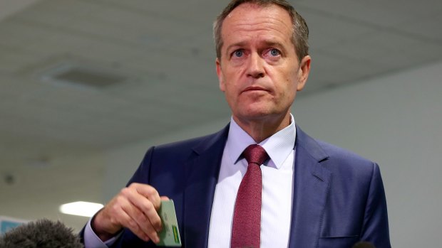 Opposition Leader Bill Shorten holds up his Medicare card at a press conference.