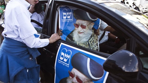 A supporter of the ultra-Orthodox Shas party holds a poster of the late Rabbi Ovadia Yosef in Bnei Brak this week.