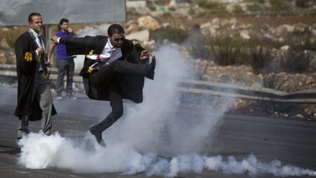 A Palestinian lawyer wearing his official robes kicks a tear gas canister back toward Israeli soldiers during a demonstration near Ramallah in the Israeli-occupied West Bank.  