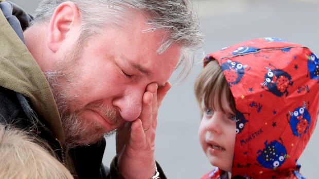 A man reacts as people lay flowers and tributes at the Hillsborough Memorial outside Anfield Stadium on Tuesday.