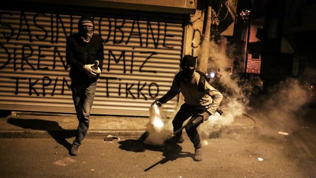 A masked and armed Kurdish protester throws back a teargas canister as they clash with Turkish police in Gazi district, in Istanbul.