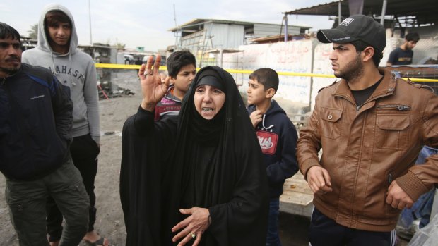 An Iraqi woman and others at the scene of the market bombing in Baghdad on Monday.