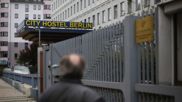 A man stands in front of the entrance of the North Korean embassy and looks to the City Hostel Berlin next door.