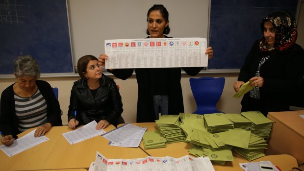 Turkish election officials show the ballot papers with signs of 15 political parties participating in election, shortly after the polling stations closed at the end of the election day, in Istanbul, on Sunday.